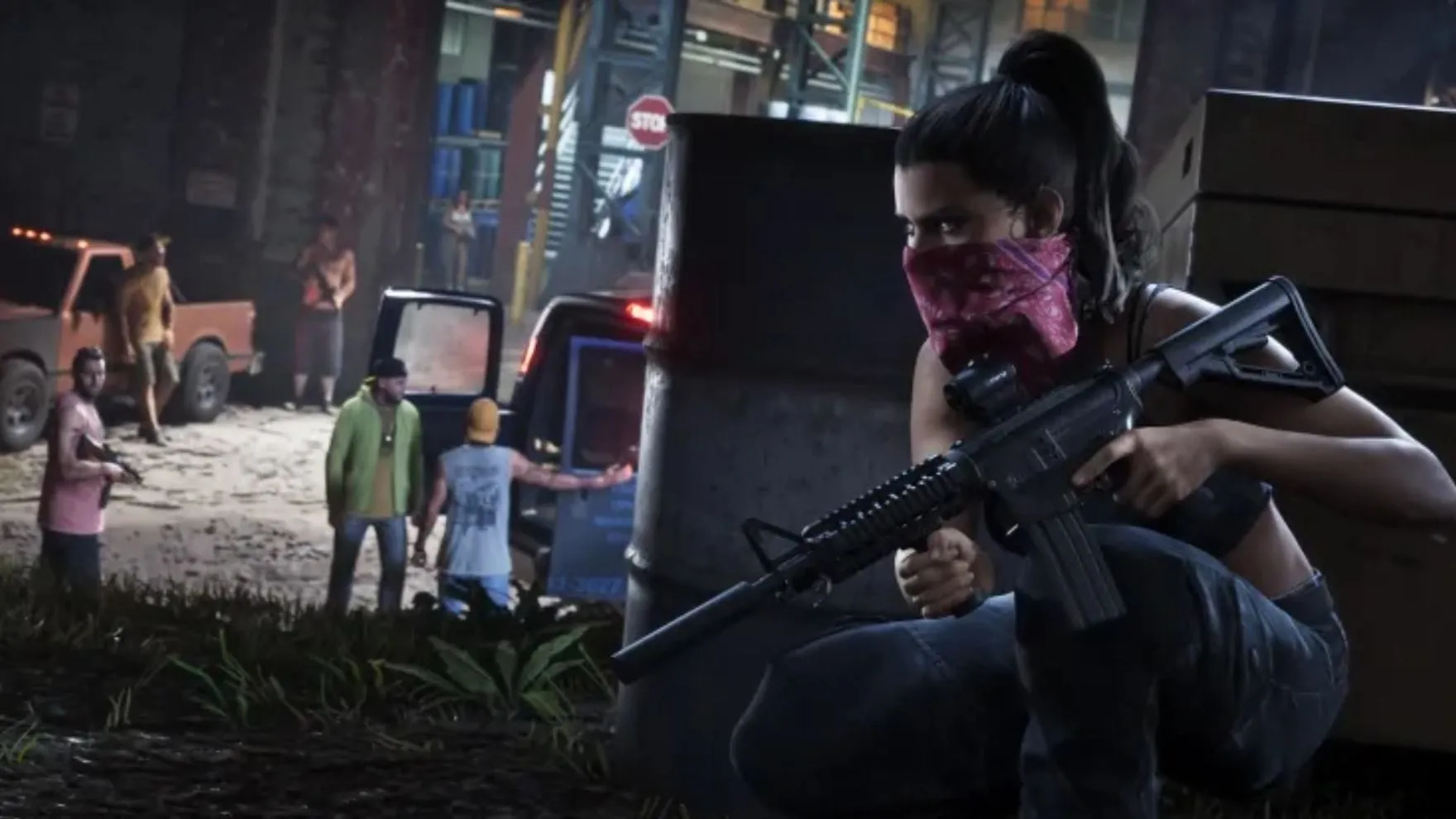 Screenshot ufficiale di GTA VI: Lucia con una bandana rossa sul volto, accovacciata dietro un barile con un fucile d'assalto, osserva uno scambio fra uomini armati vicino a due pickup