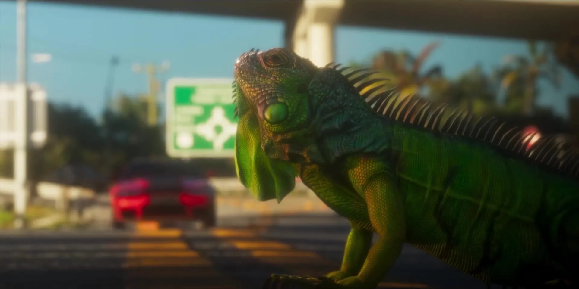 Fotogramma del Launch Trailer: un'iguana verde in primo piano a bordo strada, sotto un cavalcavia, con un'auto rossa sfocata che arriva alle spalle