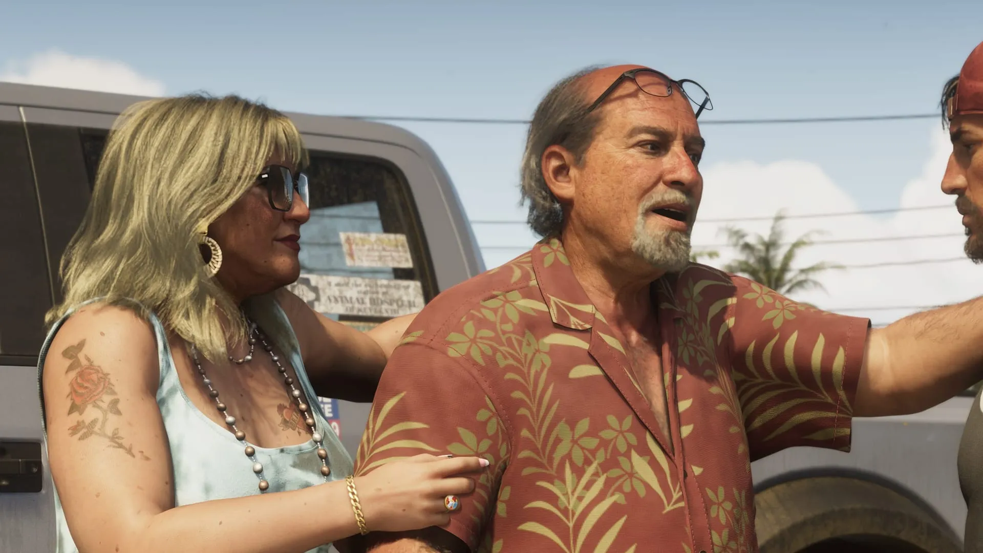 Detail of an official Brian Heder screenshot: a blonde woman with dark glasses, beaded necklaces and a rose tattoo on her arm holds Brian by the arm in front of a pickup as he talks to Jason