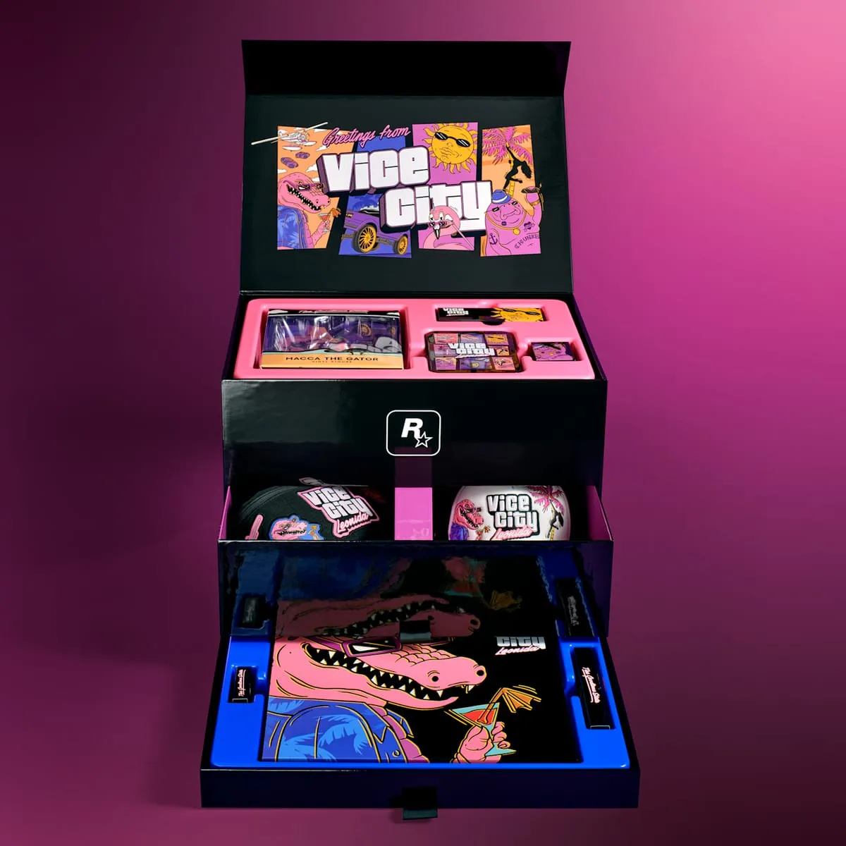 The Vice City Collection box open: the Greetings from Vice City artwork inside the lid, the boxed Macca figure and the pin tin in the top tray, the bag and cap in the middle drawer, a large Macca illustration in the bottom one
